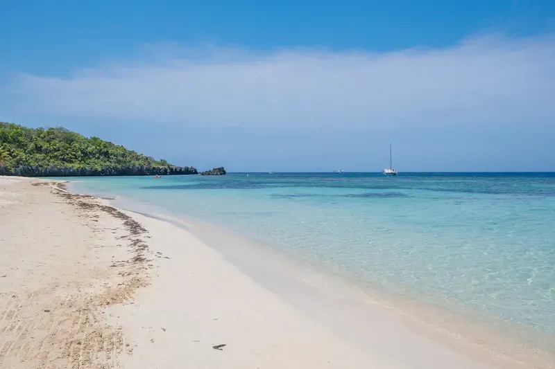 A white sandy beach with a boat in the distance.