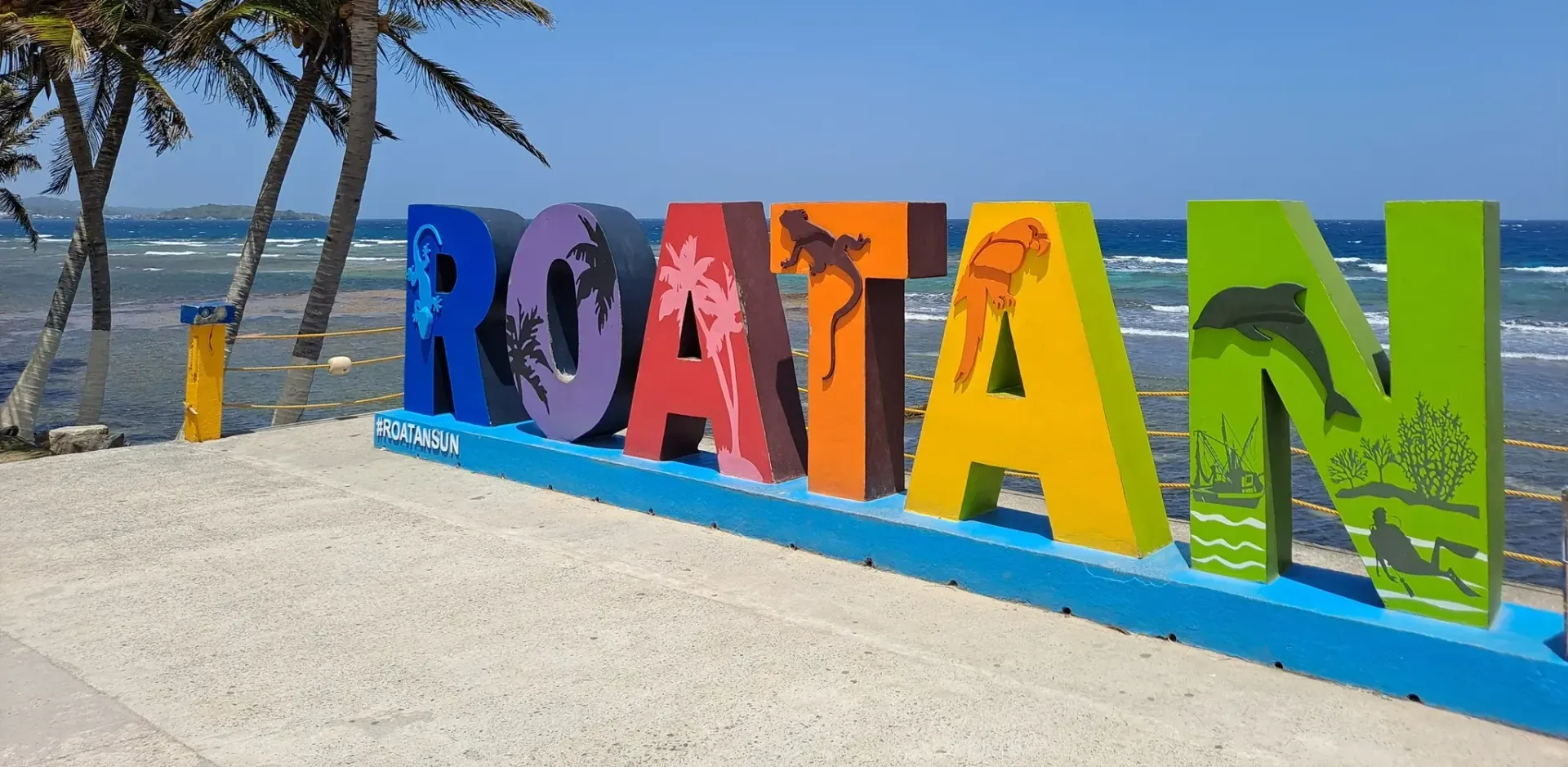 A colorful sign that says roatan on a beach
