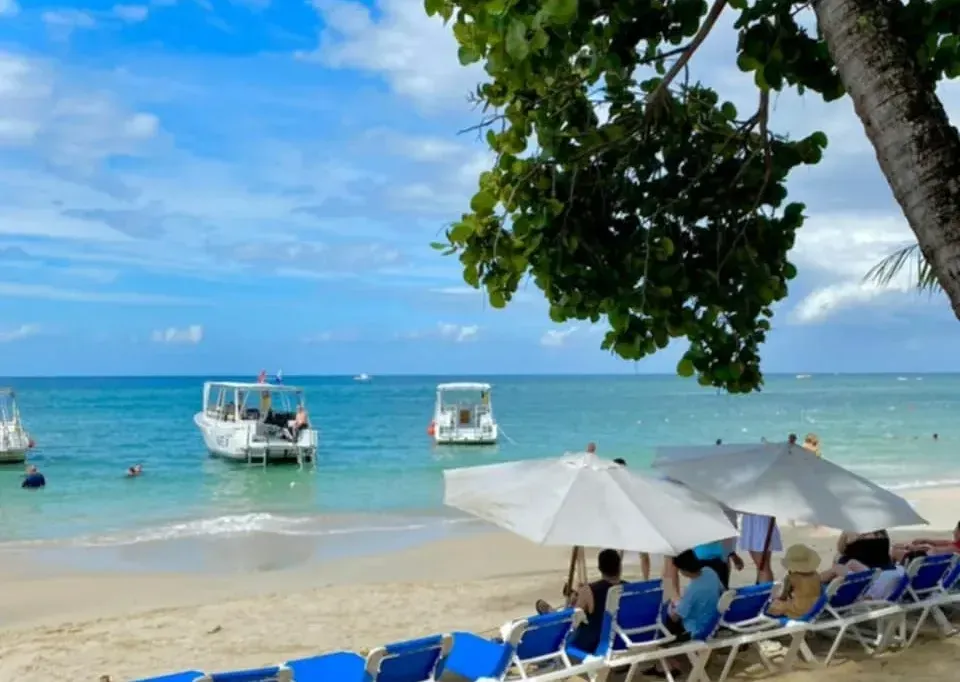 A beach with blue chairs and umbrellas and boats in the water