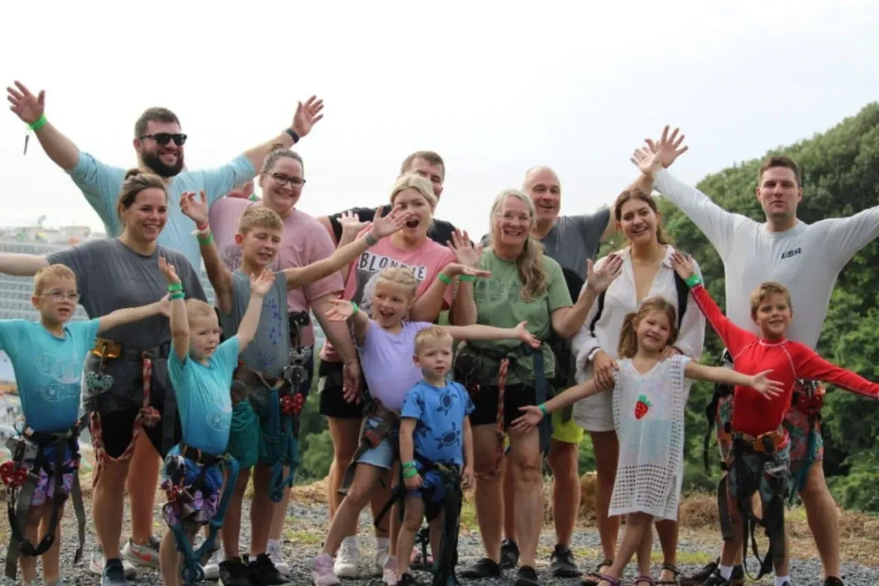 A large group of people are posing for a picture with their arms in the air.