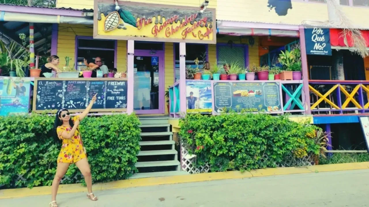 A woman is standing in front of a colorful building.