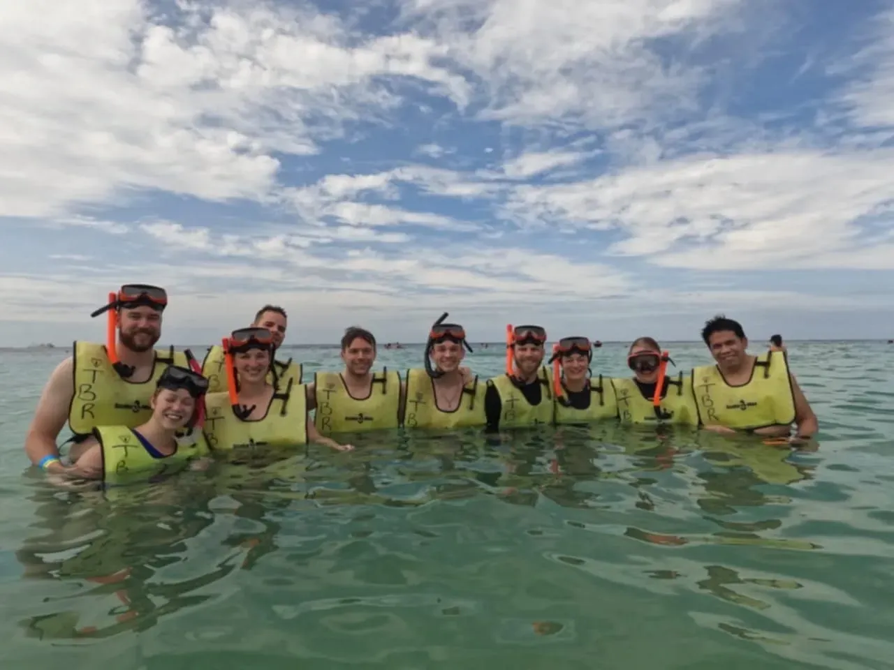 A group of people are standing in the water wearing life jackets and goggles.
