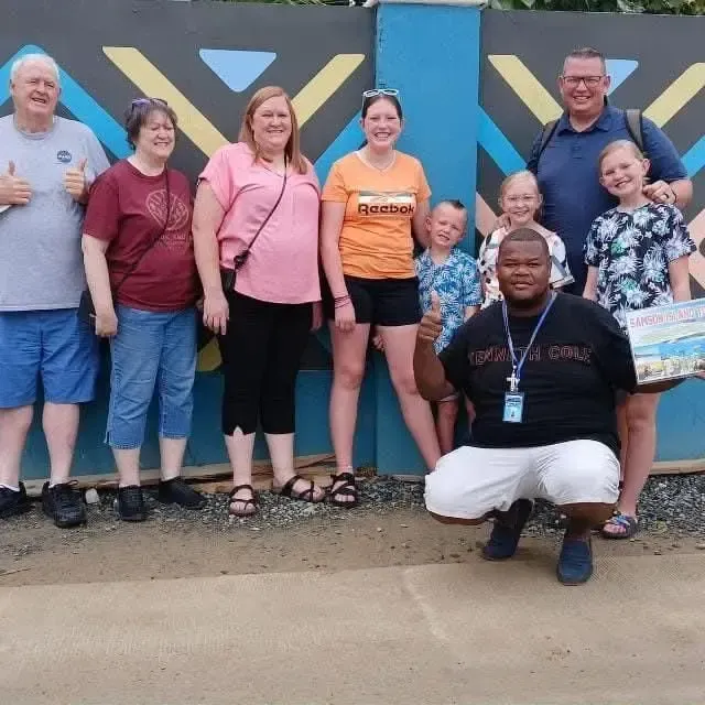 Group of people posing for a photo in front of a colorful wall; several people are smiling.