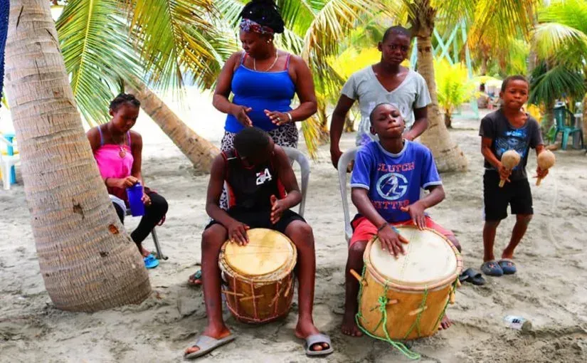 Un grupo de personas está tocando tambores en la playa.
