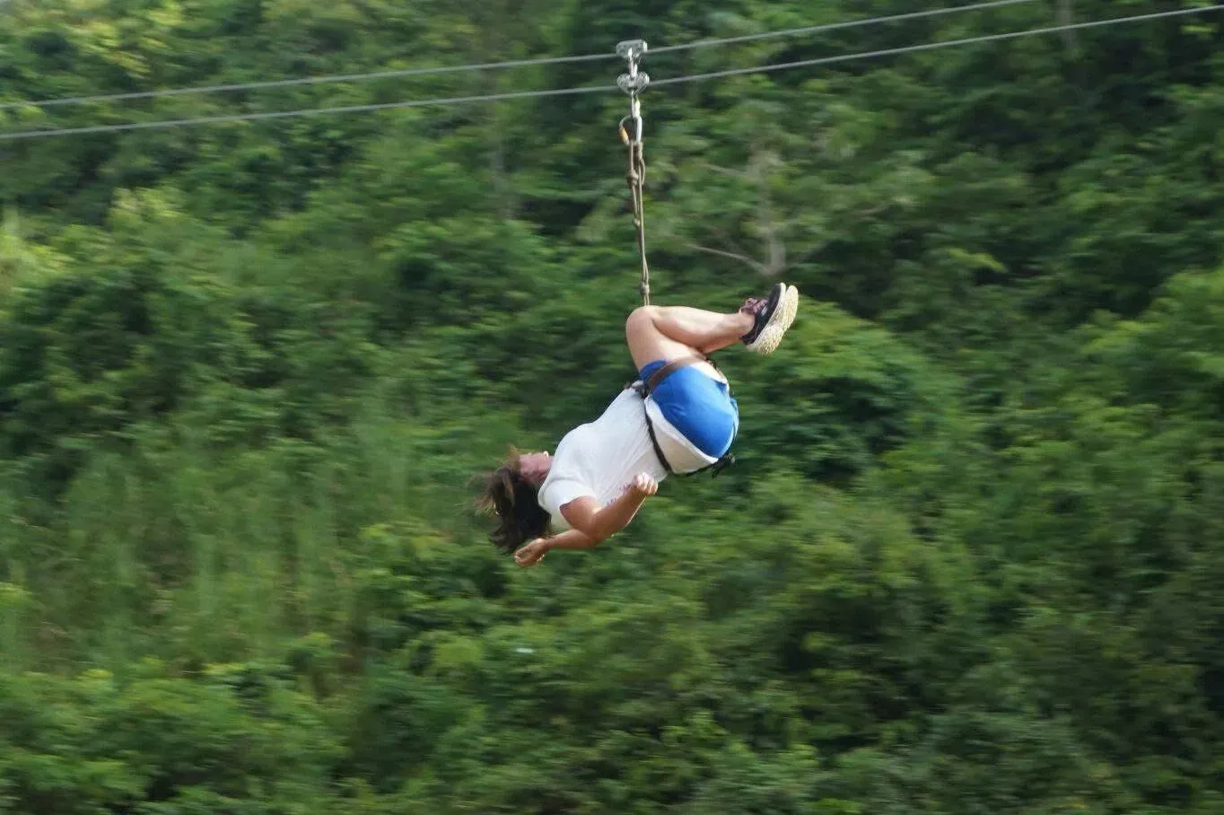 A woman is flying through the air on a zip line.