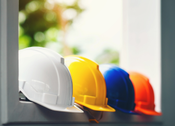 Four hardhats in a row sitting on a shelf
