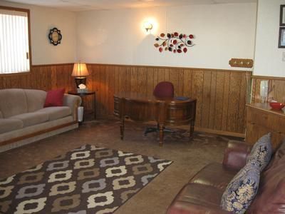 Cozy living room with brown sofas, wooden table, lamp, patterned rug, and wall decor.