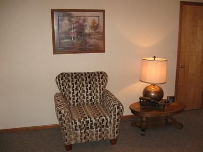 Patterned armchair beside a wooden side table and lit lamp in a quiet room