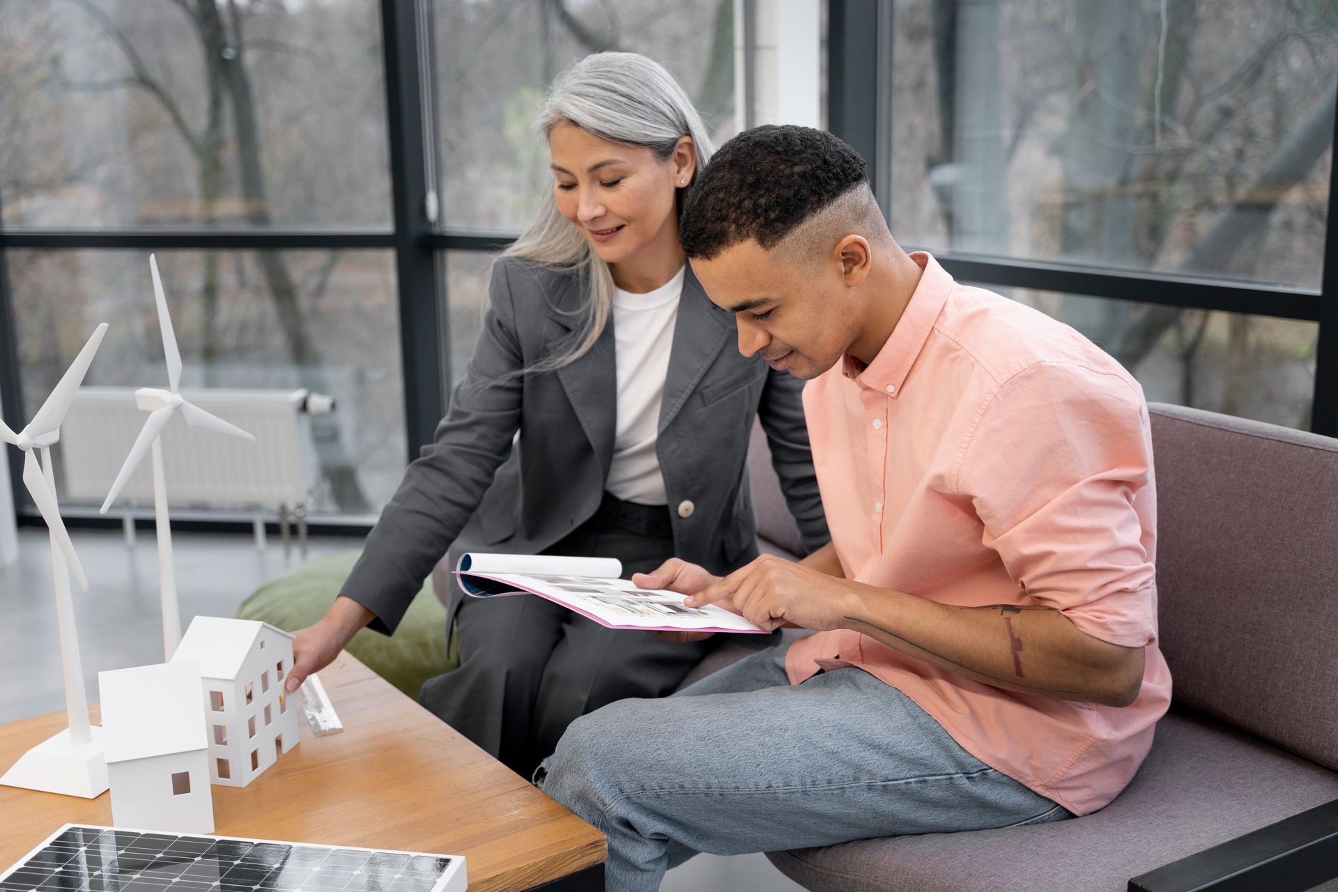 A man and a woman are sitting on a couch looking at a model house.