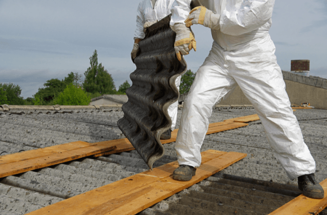 Two men in white overalls are working on a roof.