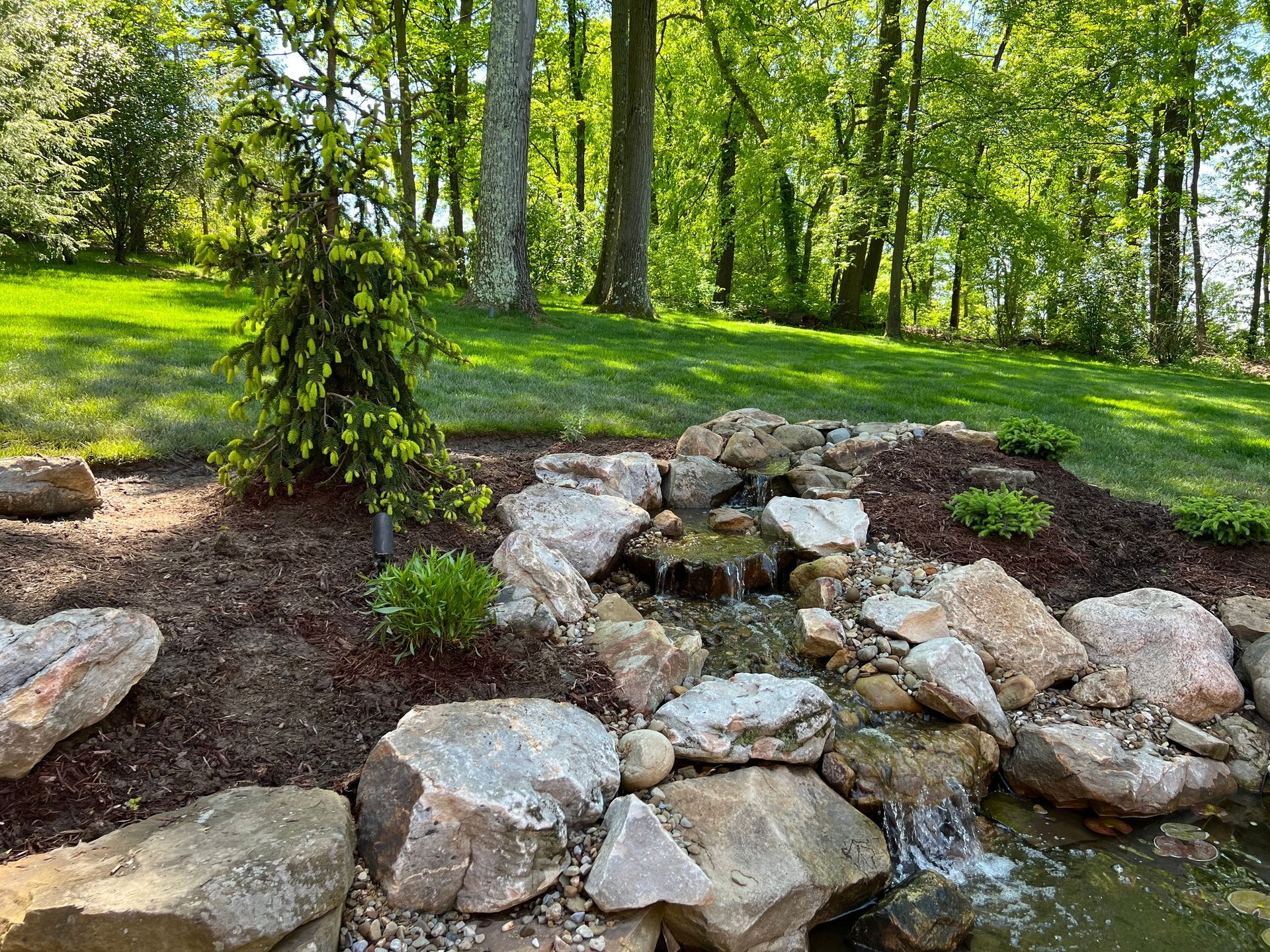 Rock garden with a small water stream in a green wooded park
