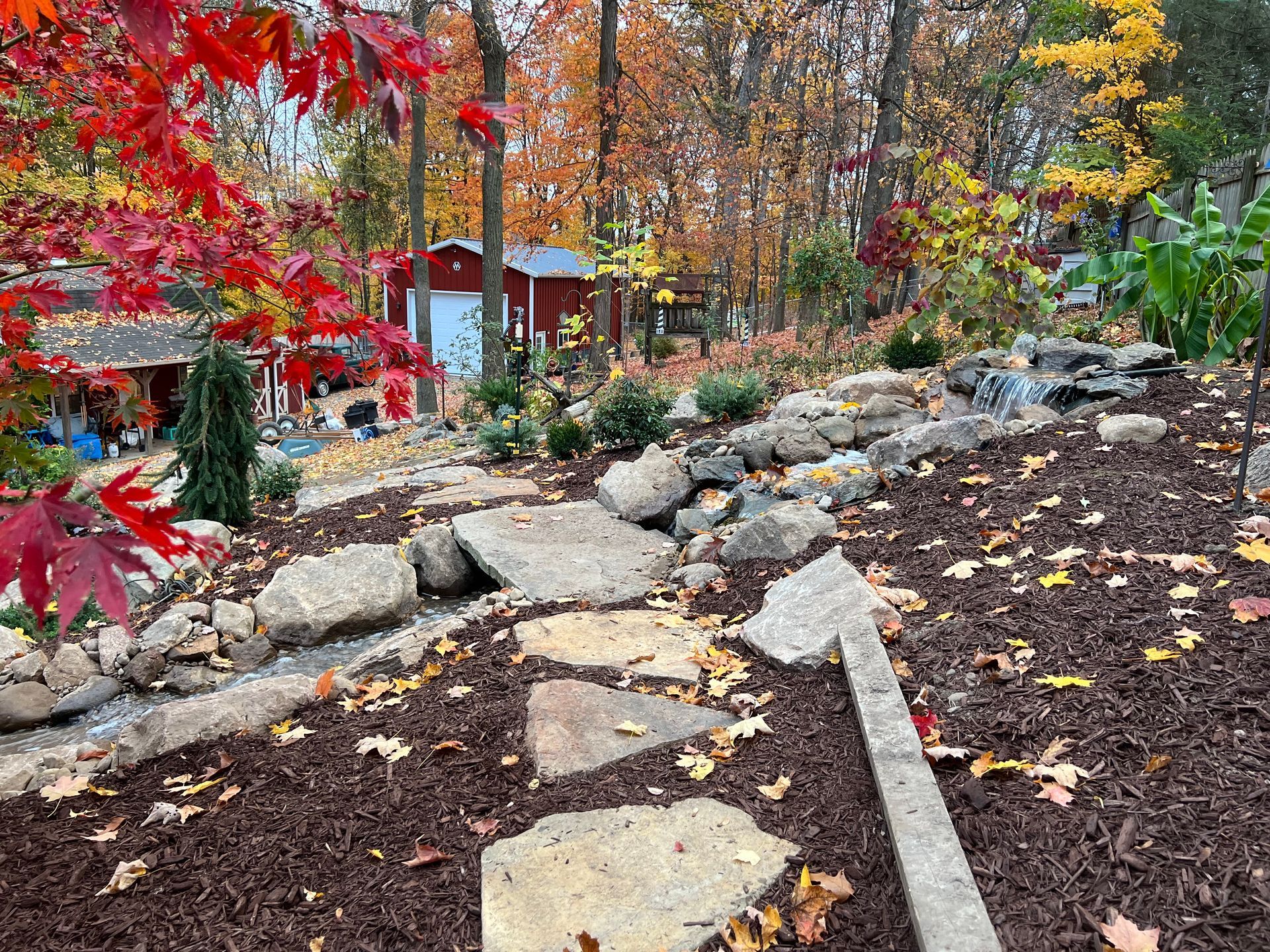 Rock garden path beside a forest with autumn trees and red leaves