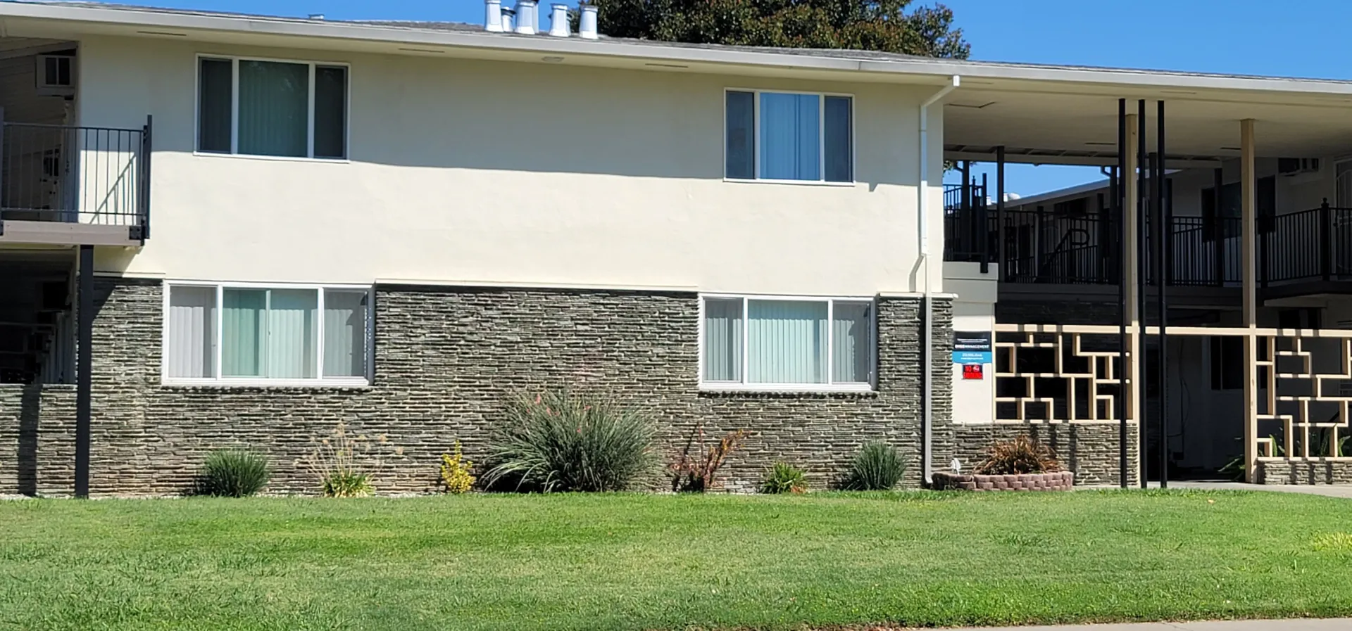 a large white house with a stone facade is sitting on top of a lush green lawn .
