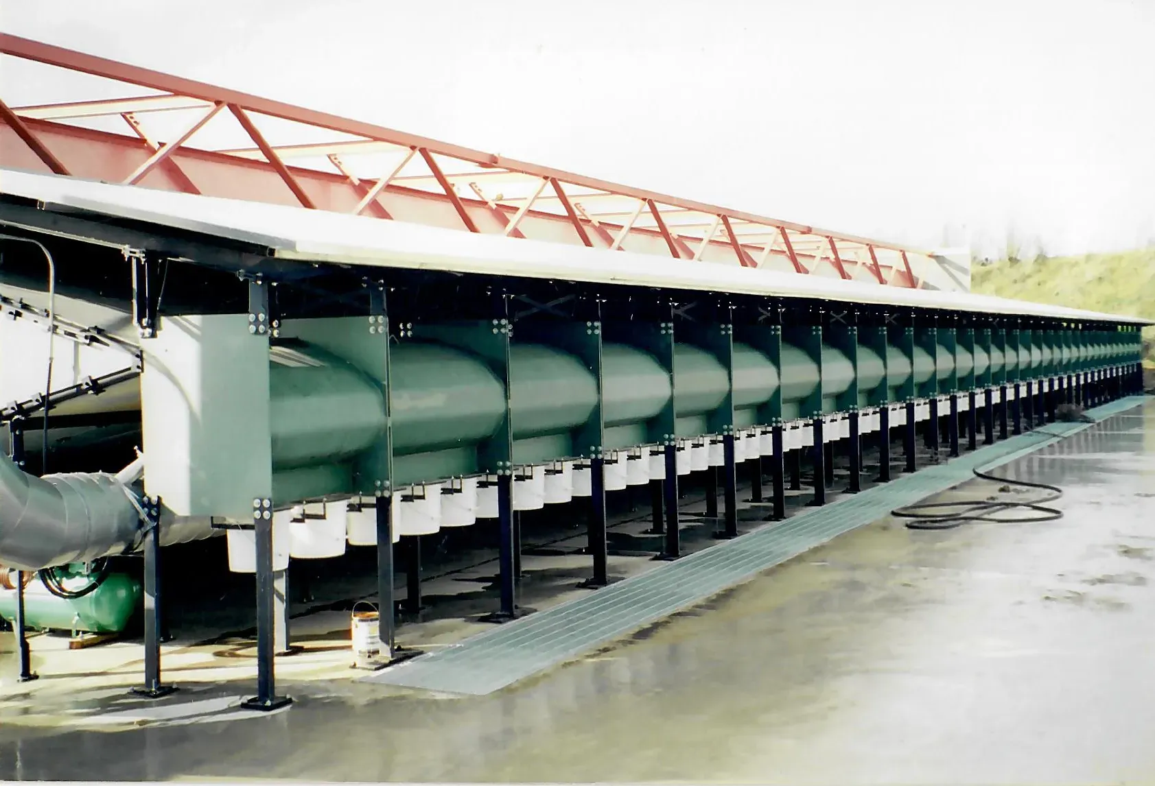 a row of green pipes are lined up under a red roof