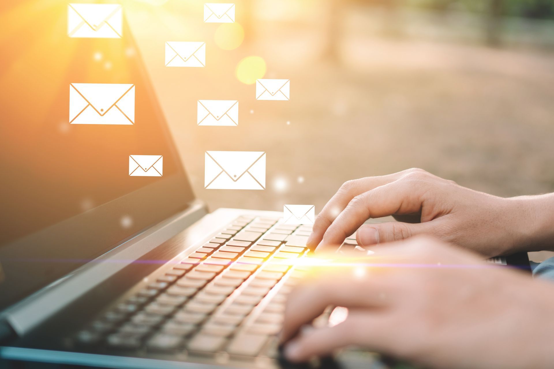 a person is typing on a laptop computer with envelopes coming out of the screen .