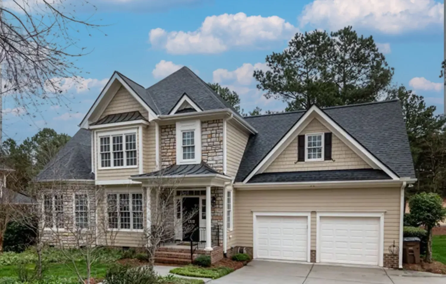 a large house with a gray roof and white garage doors