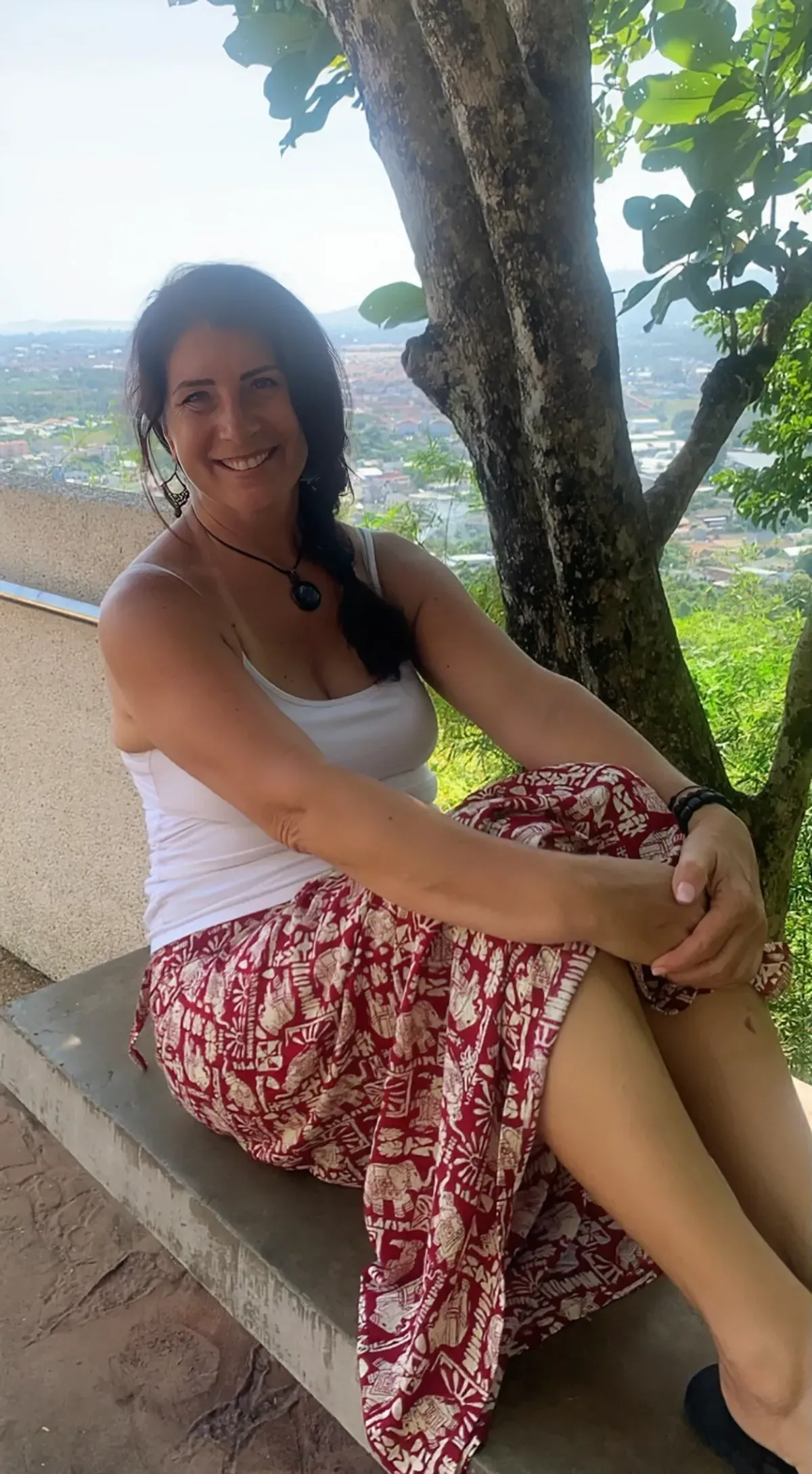 a woman is sitting on a bench under a tree .