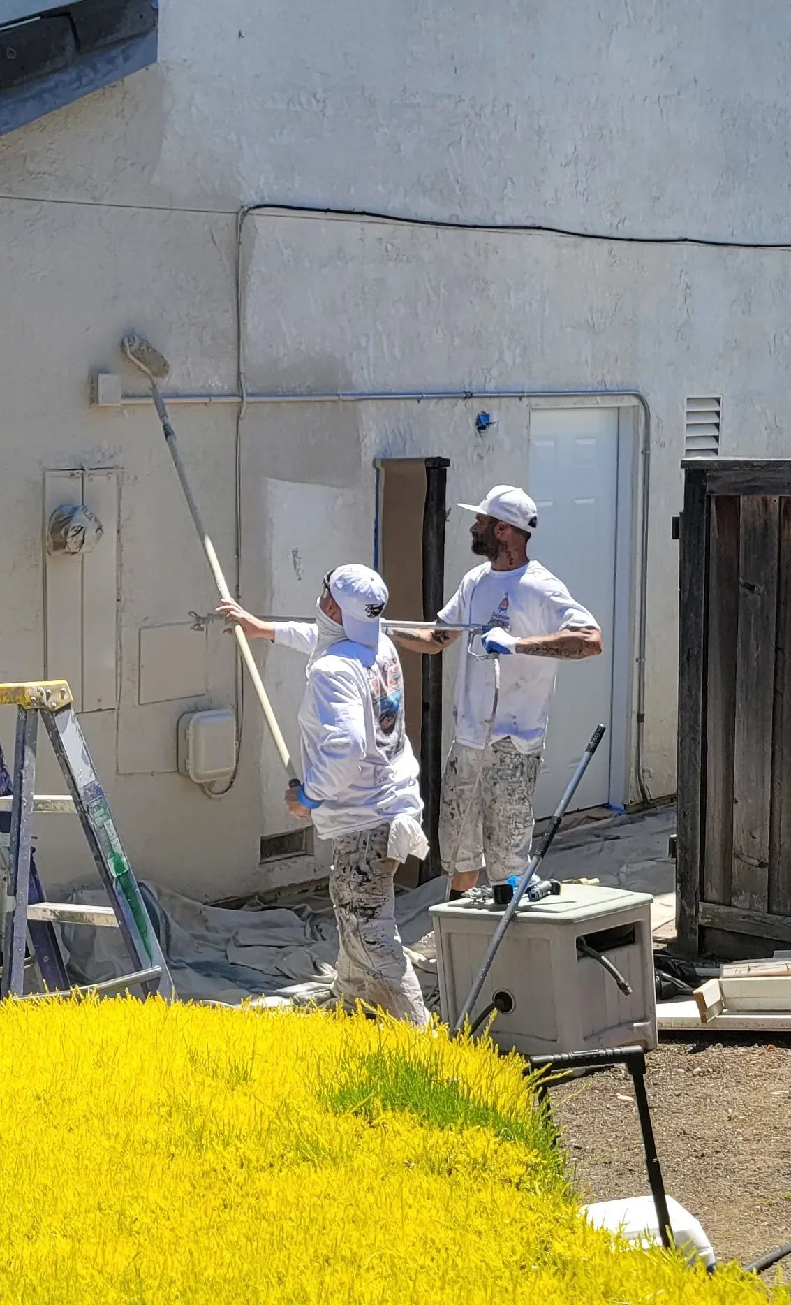 two men are painting the side of a building .