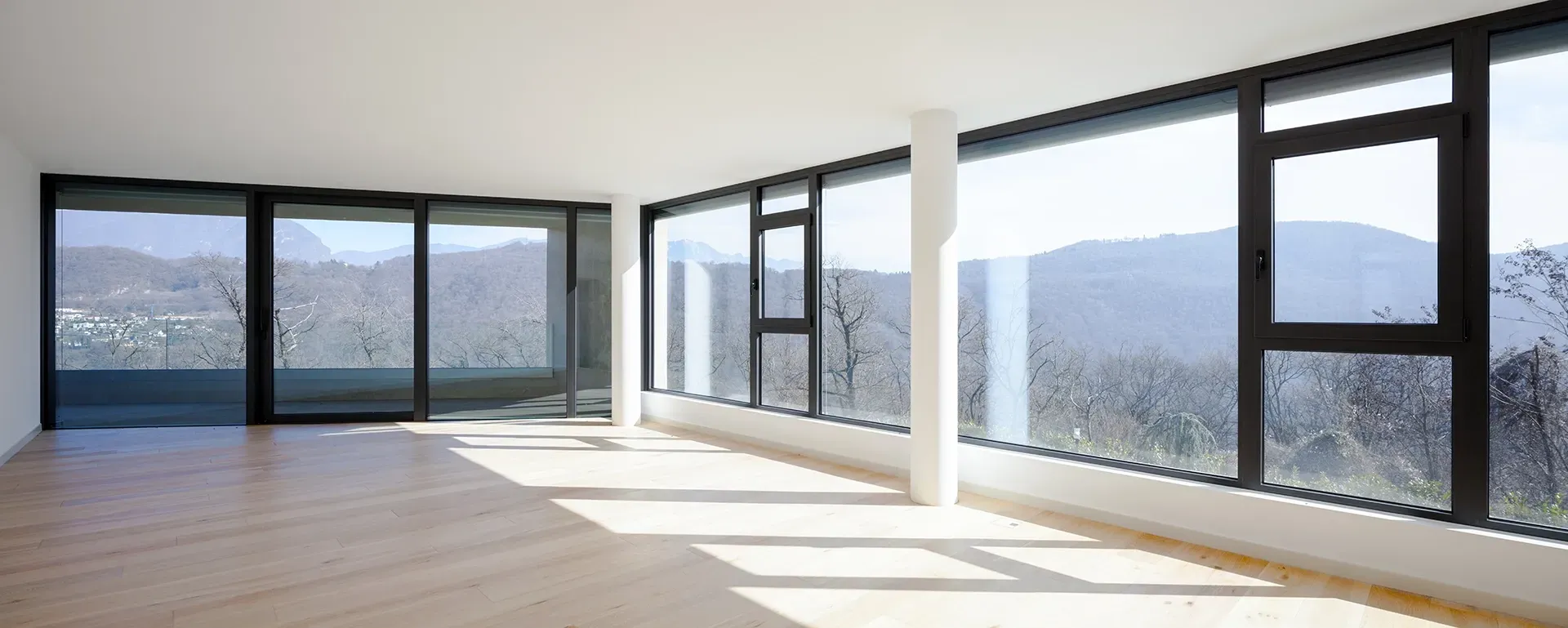 an empty room with a lot of windows and a view of the mountains .