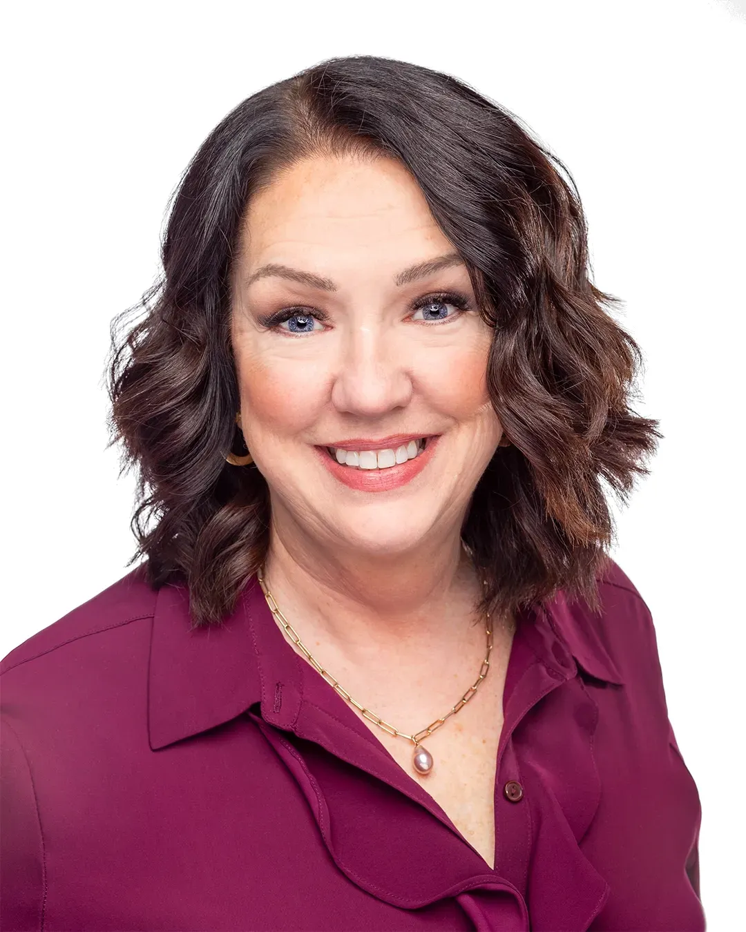 A woman in a purple shirt and necklace is smiling for the camera.