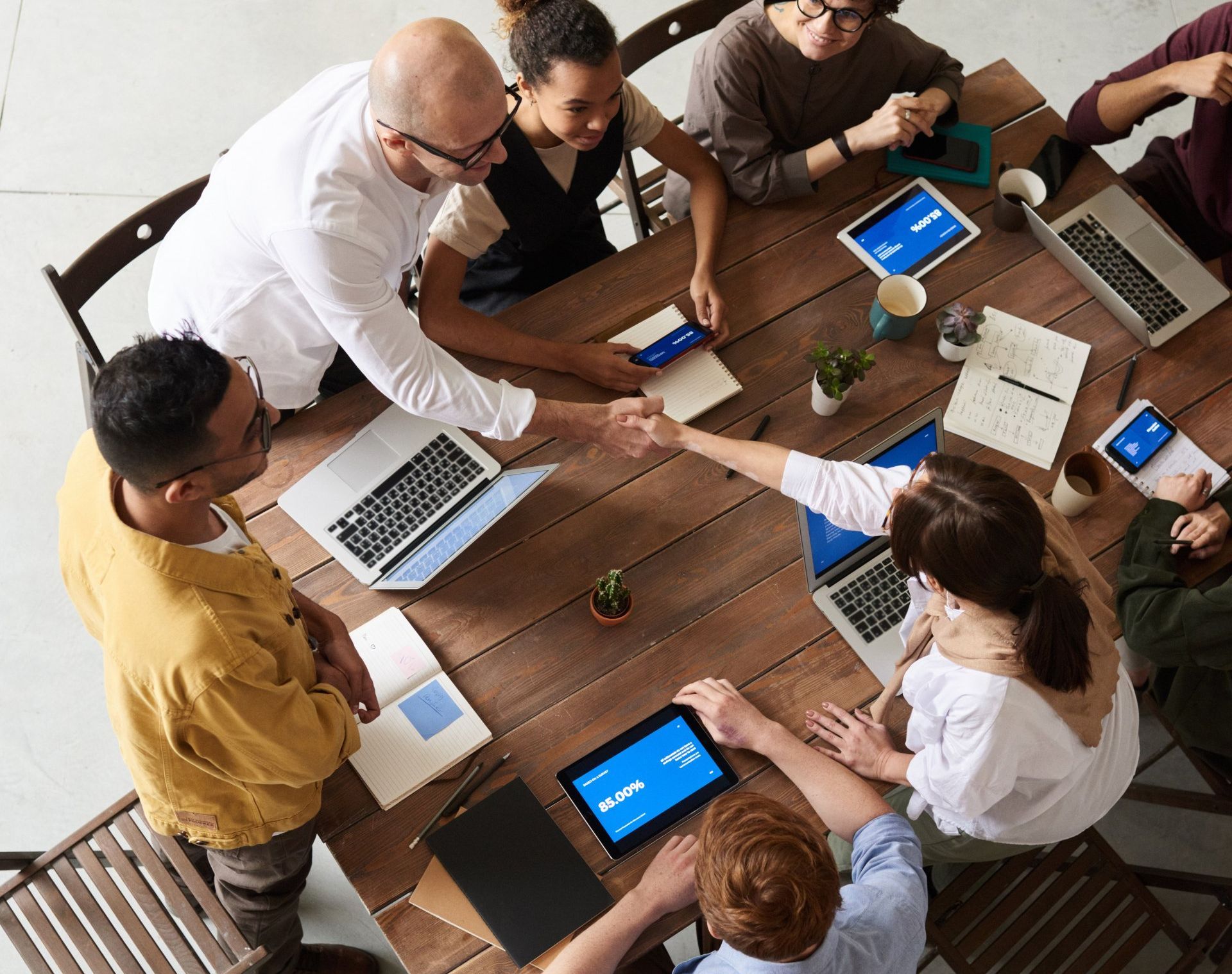 a group of people are sitting around a table shaking hands .