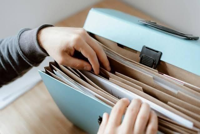 hand reaching into a blue filing system full of papers