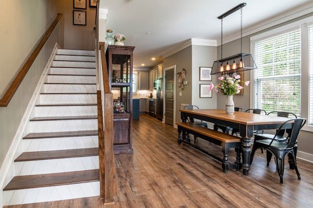 a kitchen and dining areas with dark wood flooring and staircase to the second floor