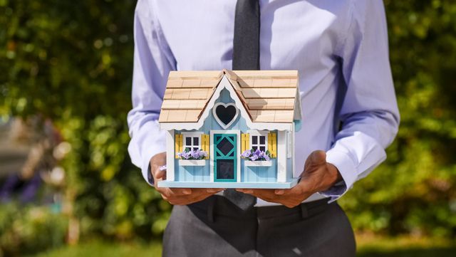 a person holding a wooden house model