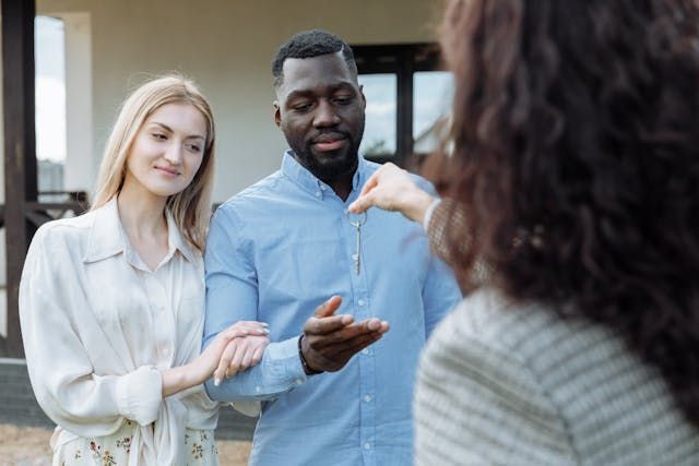 real estate agent handing keys to two people
