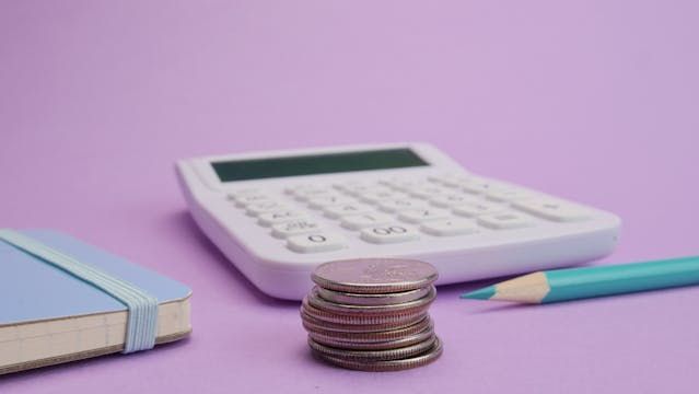 a stack of coins in front of a calculator