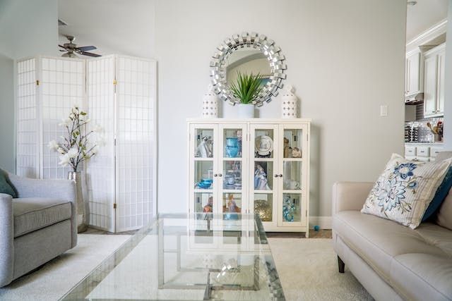 a white living room with light furniture and a glass table