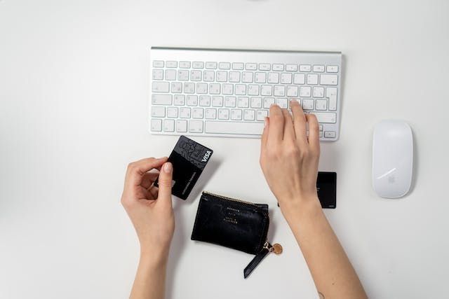 hand holding a credit card and using a computer mouse for an online rent payment