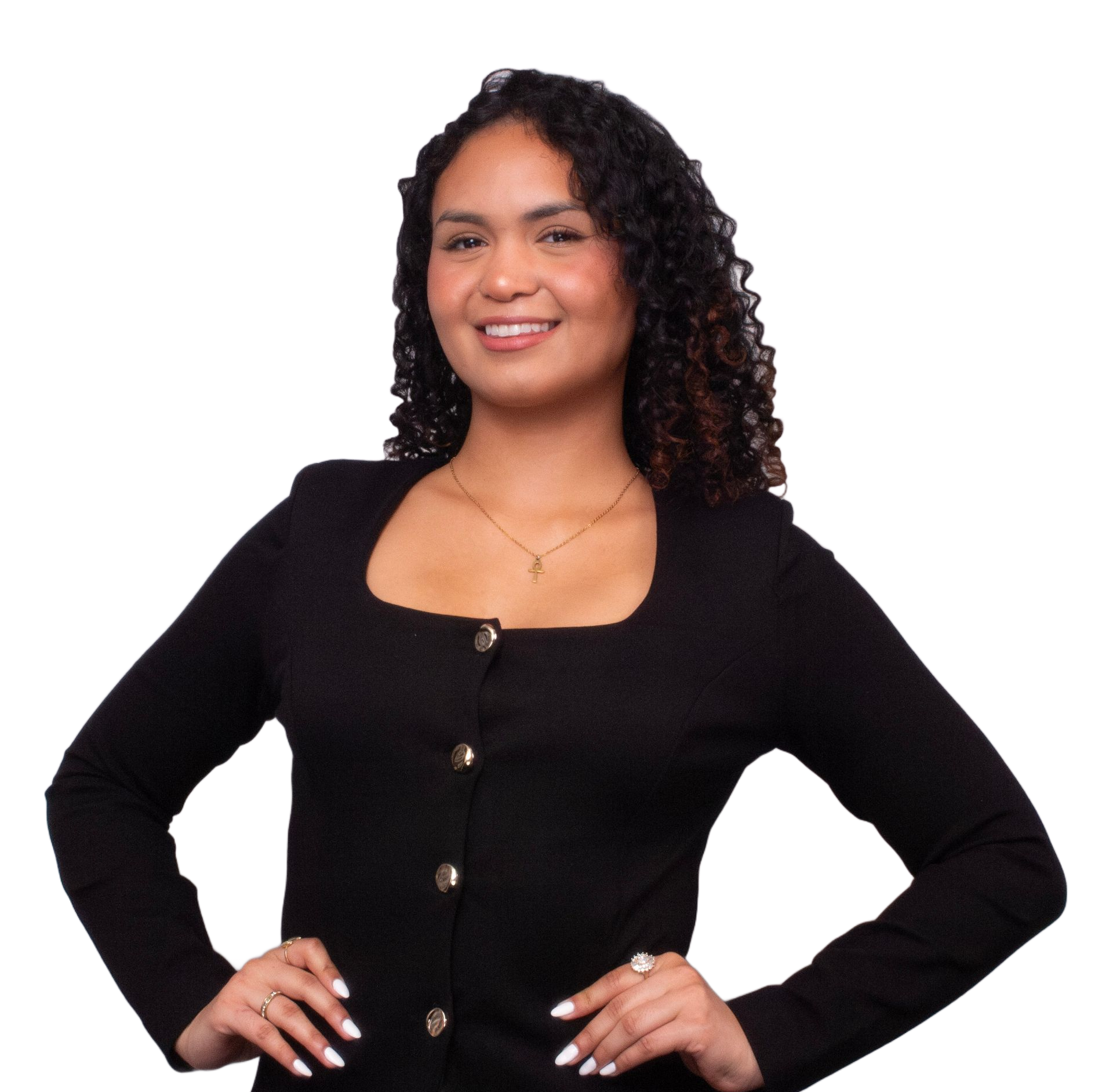 Woman with curly dark hair smiles, wearing a black top, hands on hips.