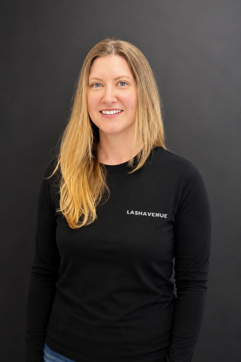 Woman in black shirt, dark hair, smiling, in front of a dark backdrop.