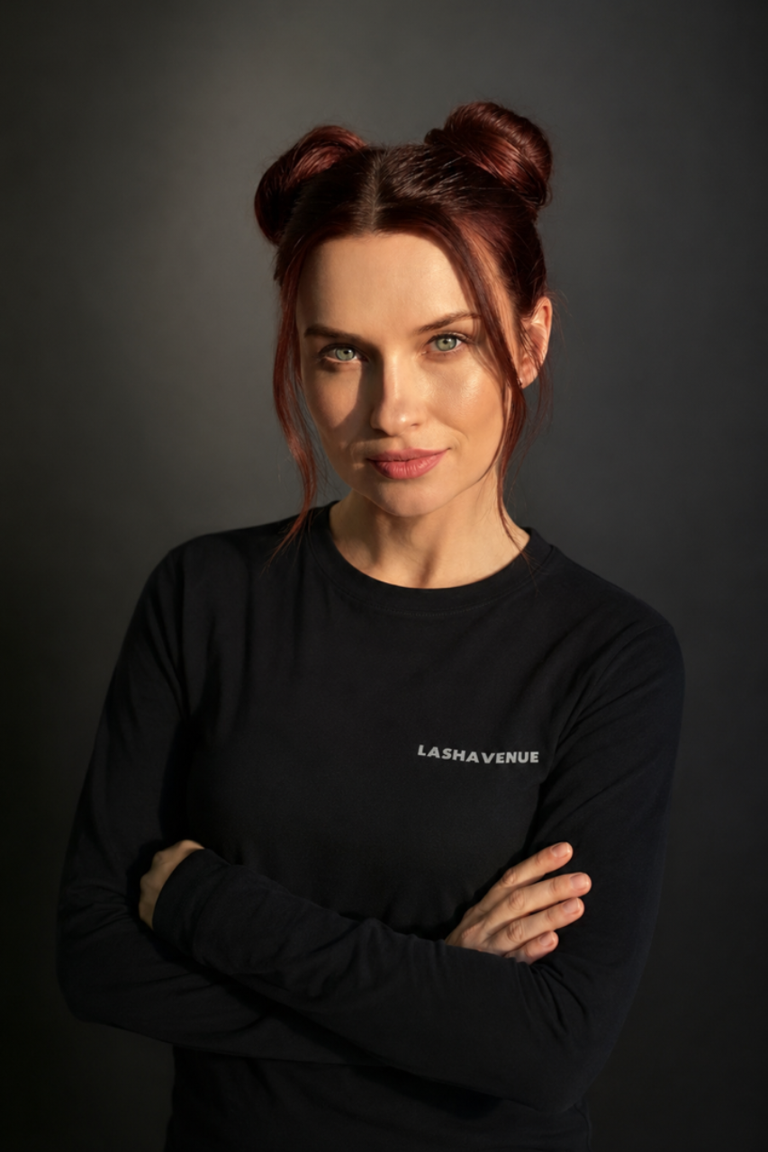 Woman in black shirt, dark hair, smiling, in front of a dark backdrop.