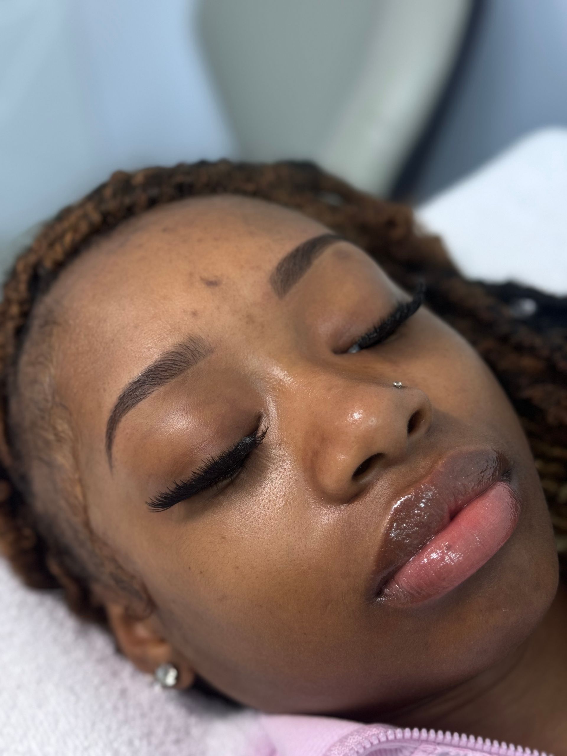 Woman with closed eyes, fresh facial, applied lip gloss.