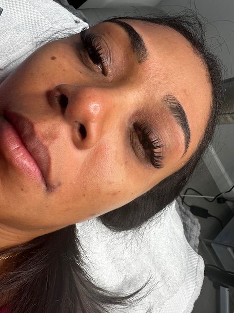 Woman with dark eyebrows and lashes, eyes closed, resting on a white surface.