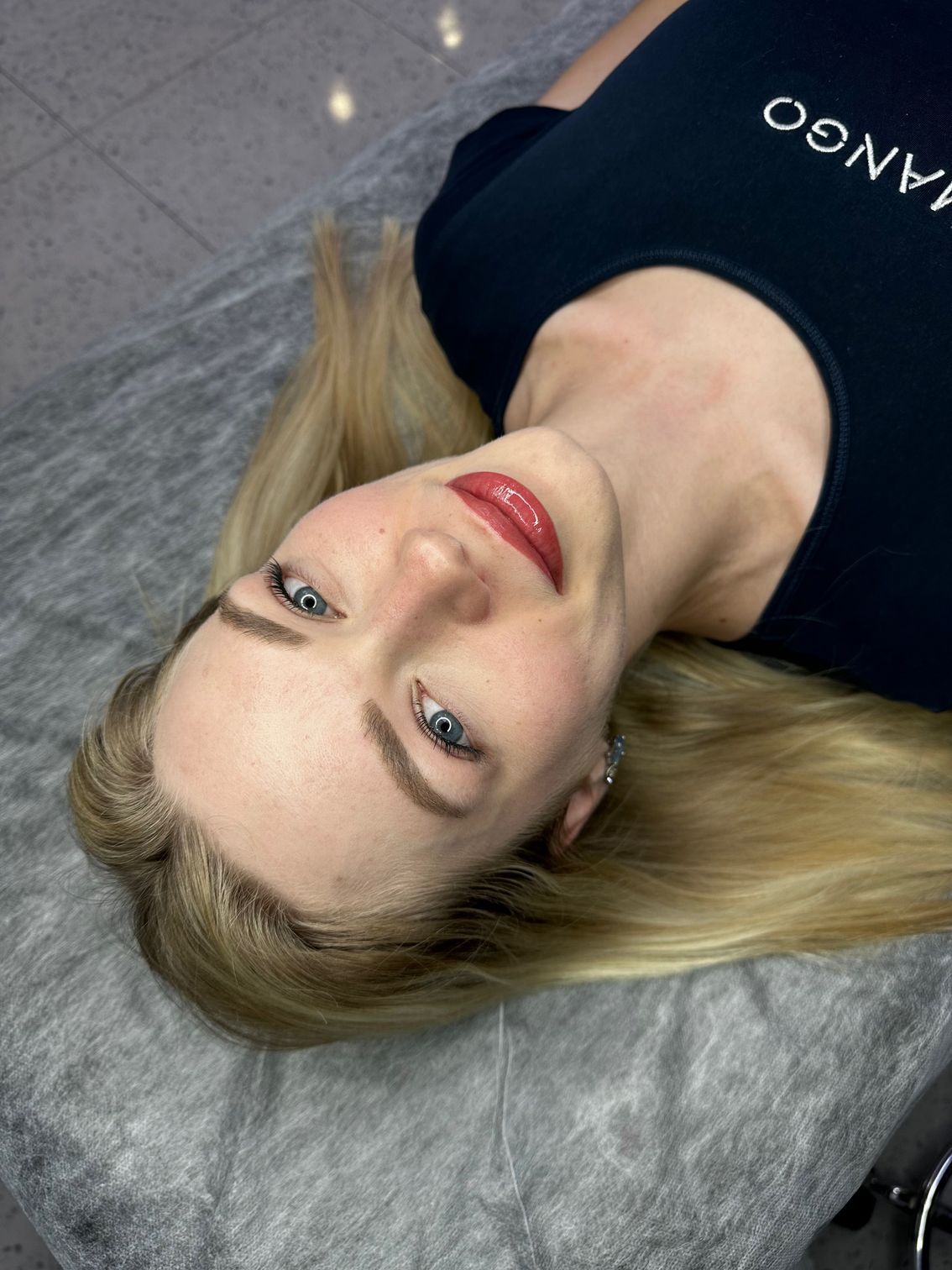 Woman with blonde hair and red lipstick lying down.
