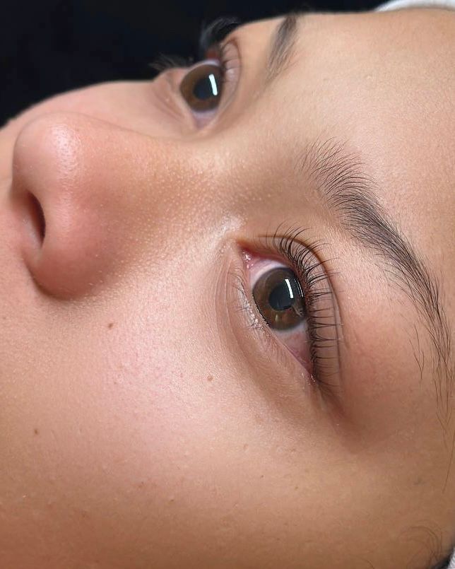 Close-up of a person's eye, showing brown iris, lashes, and eyebrow. Skin is visible.