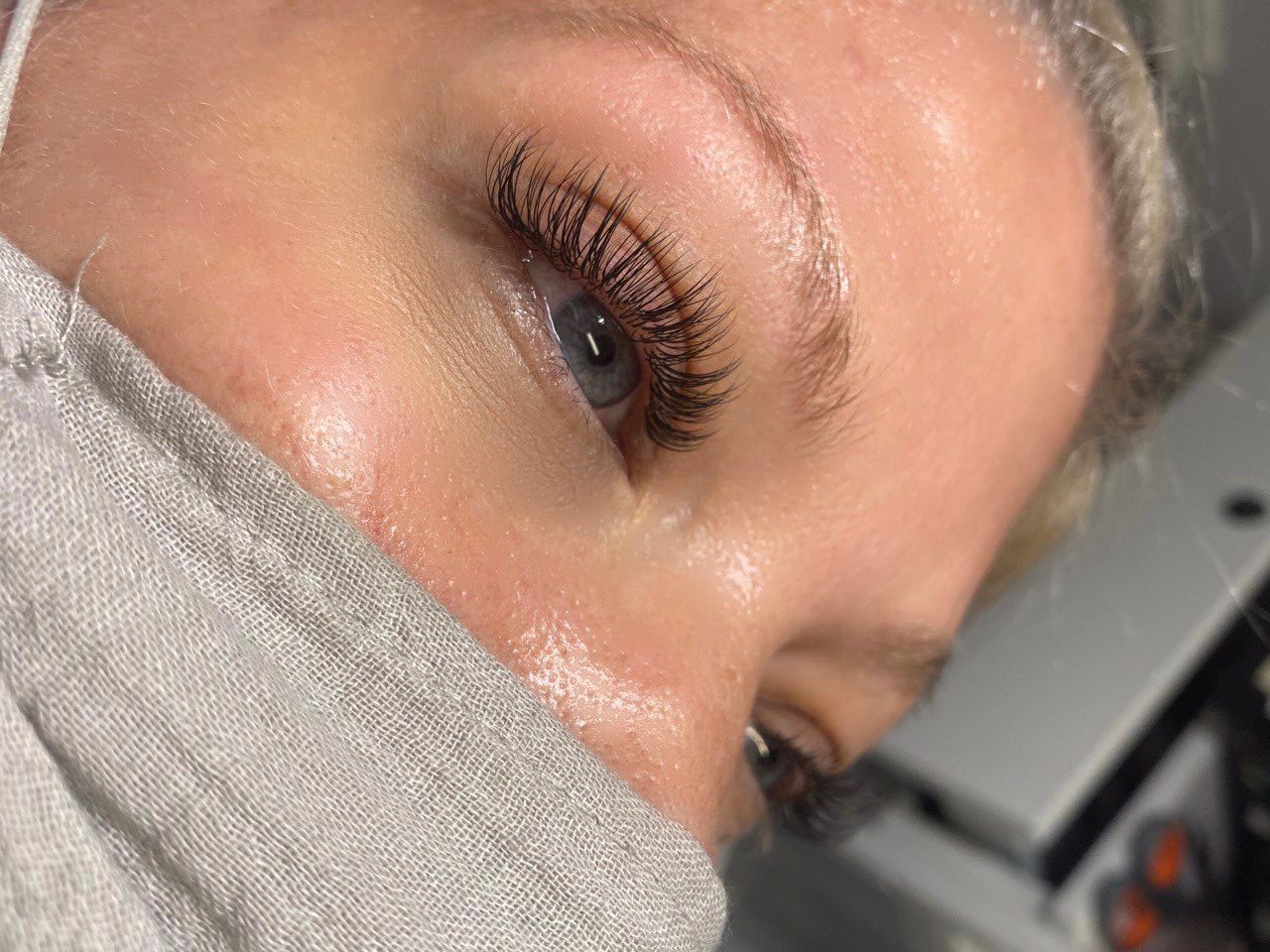 Close-up of a person's eye, with long, dark lashes, pale skin, and a mask pulled down.