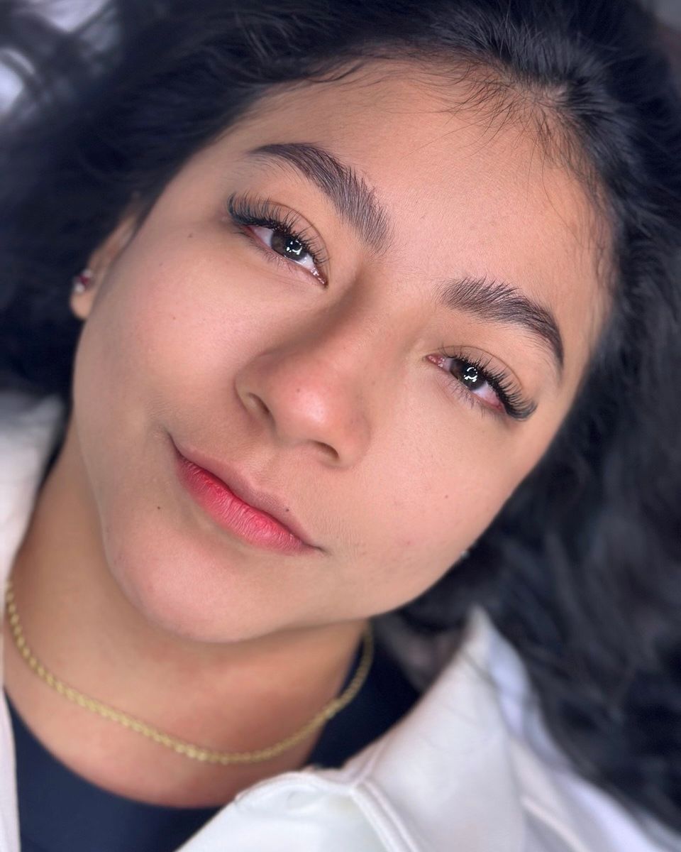 Woman with new eyebrow microblading and eyelash extensions, smiles.