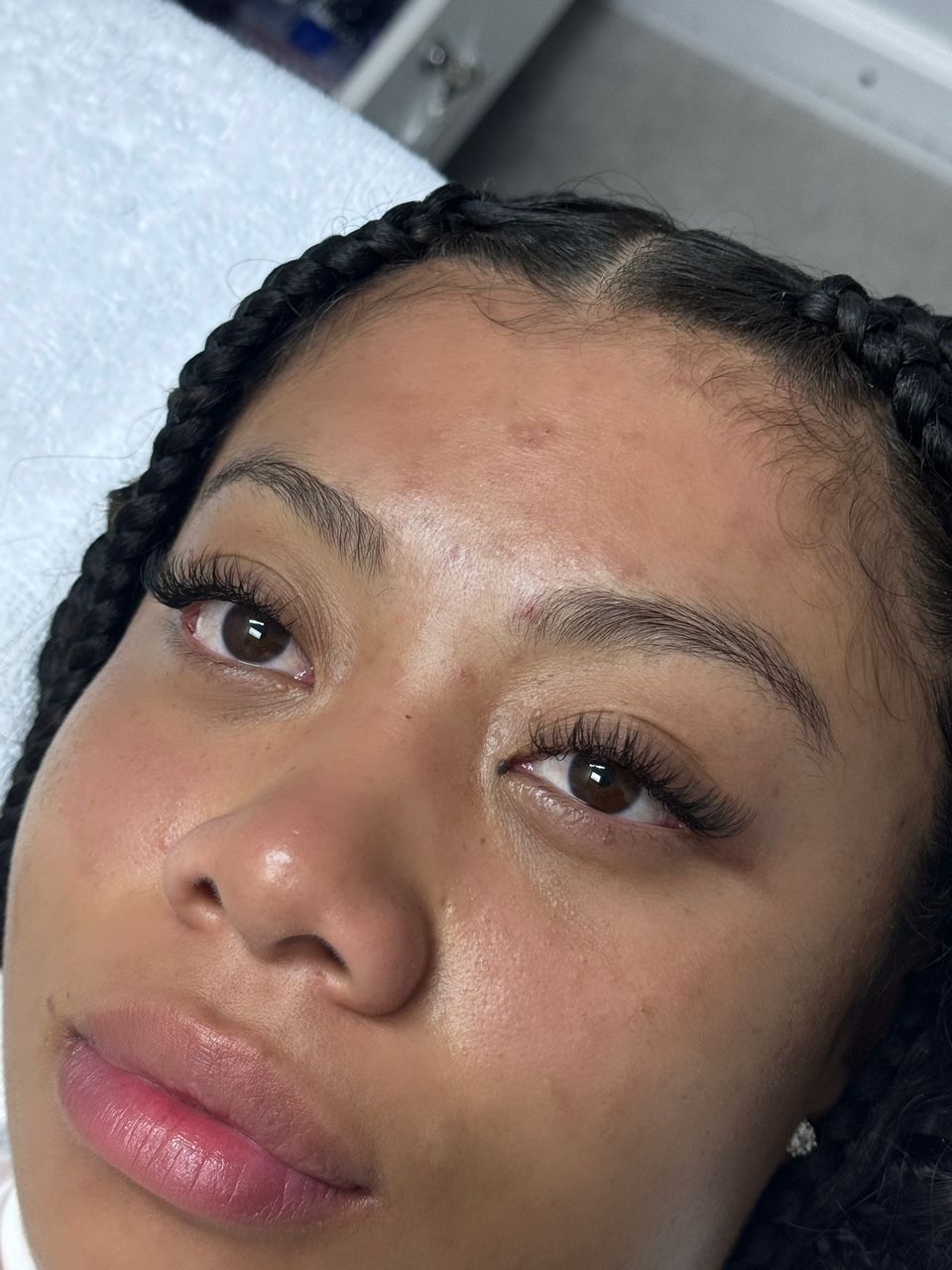 Woman with braided hair, close up view; eyelashes, eyebrows; looking towards the camera.