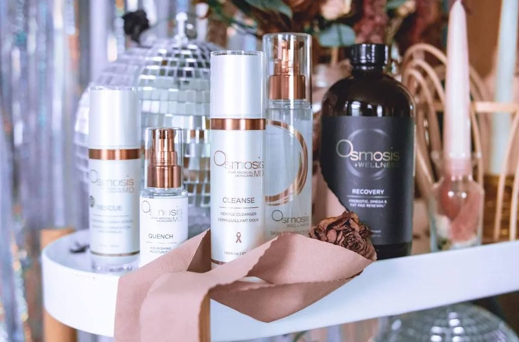 Skincare products arranged on a mirrored surface with a disco ball, ribbons, and flowers.