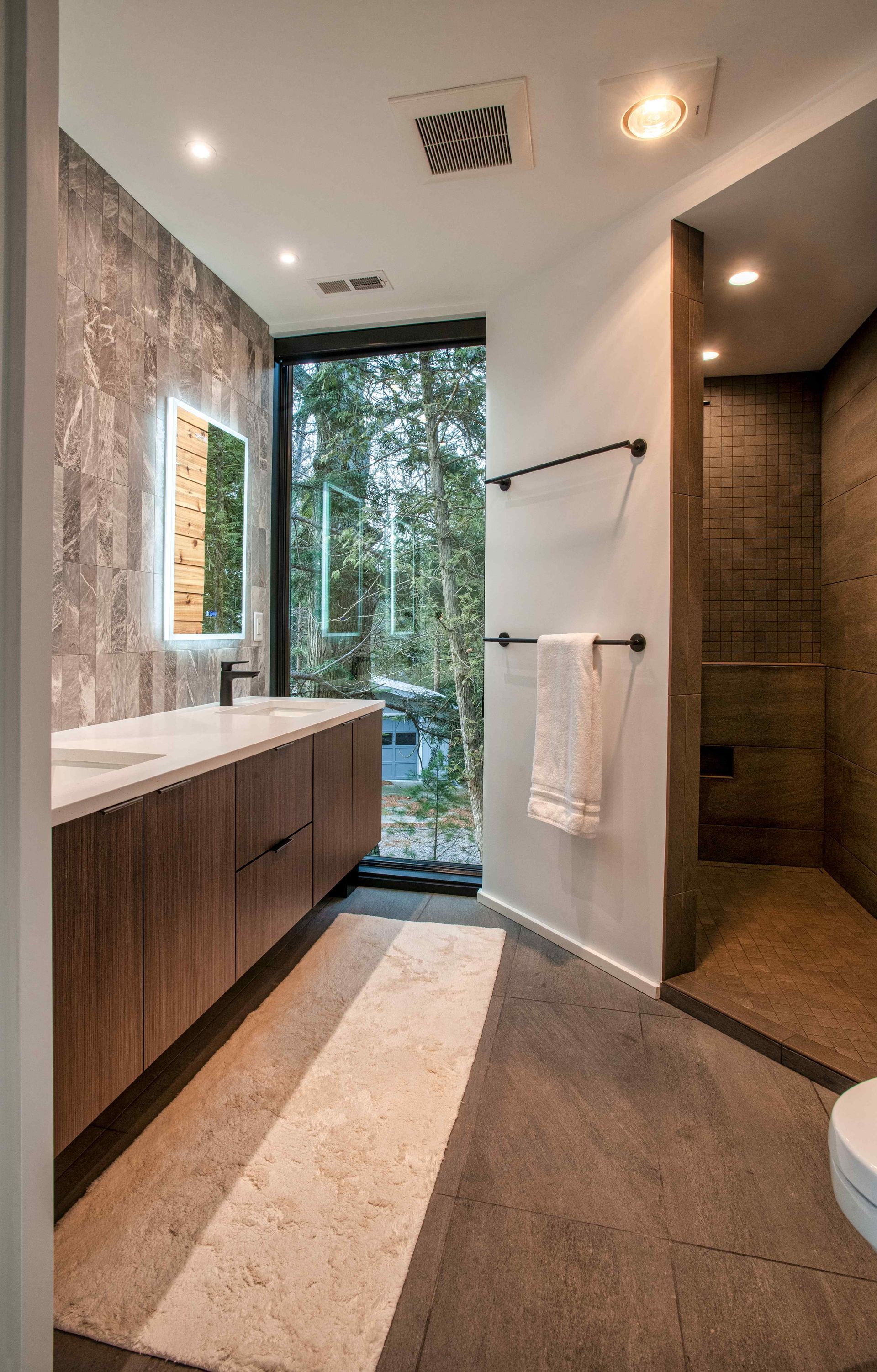 A bathroom with two sinks , a toilet and a walk in shower.