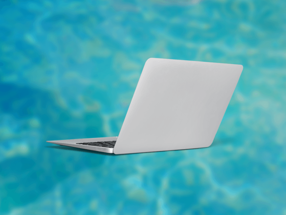 A laptop computer is sitting in the water of a swimming pool.