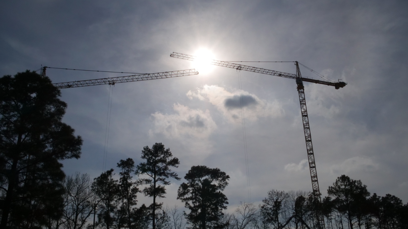 A Construction site in The Woodlands featuring a high-rise building under development with construction equipment and workers visible.