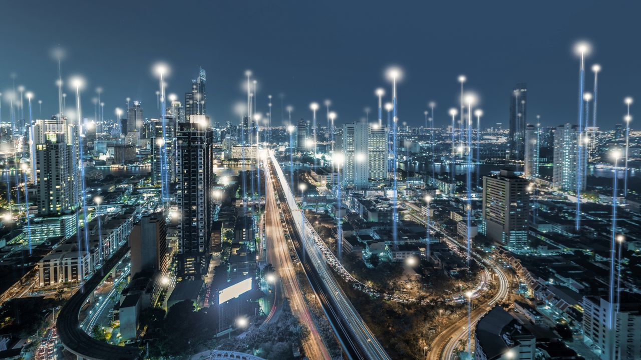 Nighttime city skyline with bright lights and highways cutting through dense urban buildings