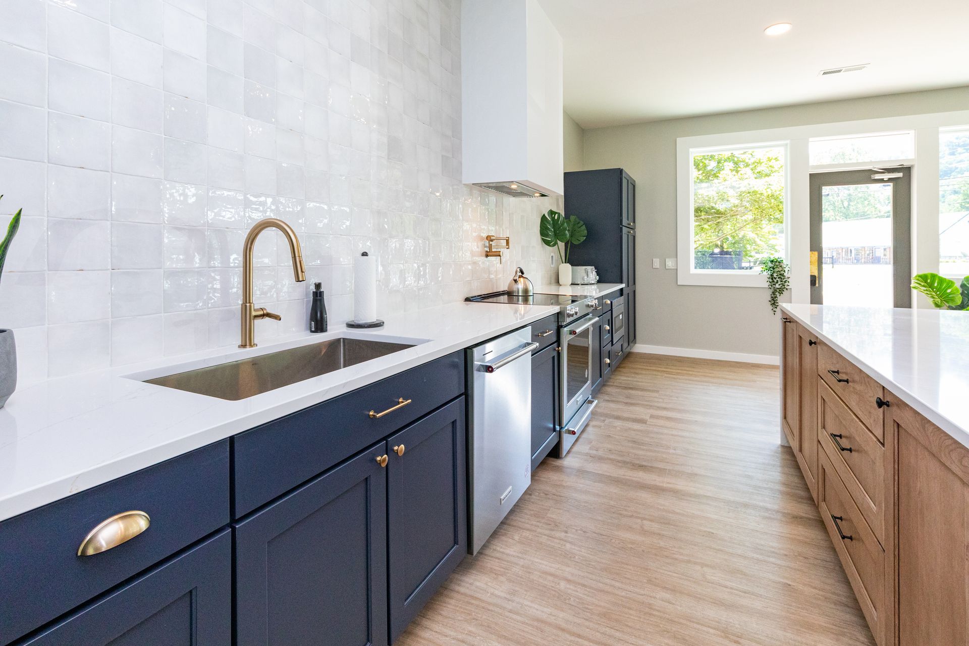 A kitchen with blue cabinets , white counter tops , stainless steel appliances and a sink.