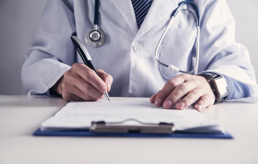 Doctor writing notes on a clipboard in a white coat – Tewantin Medical Centre in Noosa, QLD