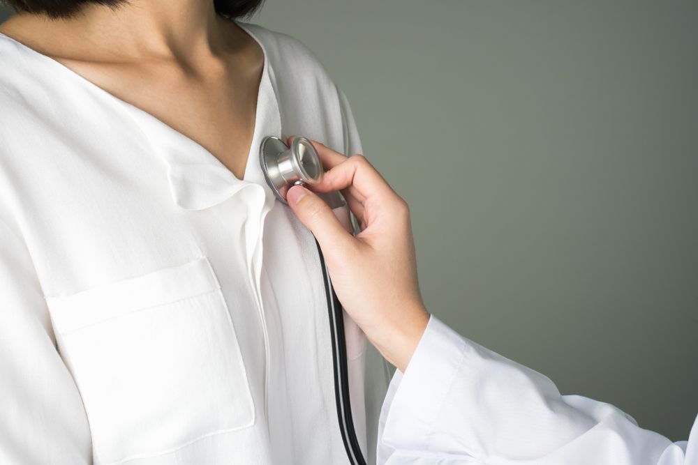 Doctor using a stethoscope to listen to a patient's chest in a white coat — Tewantin Medical Centre In Tewantin, QLD